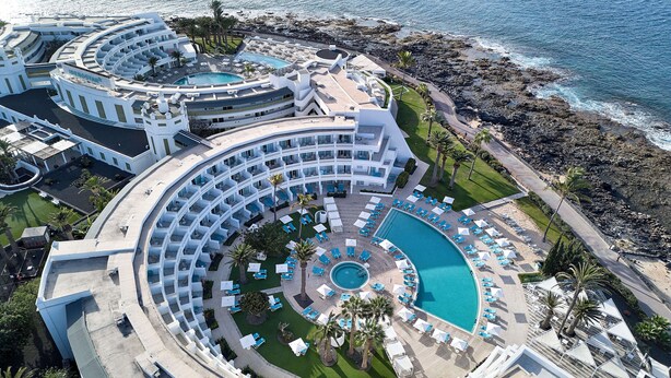 A resort with multiple circular pools, a beachside location, and a central courtyard with lounge chairs and palm trees. - Iberostar Selection Lanzarote Park (Yaiza)