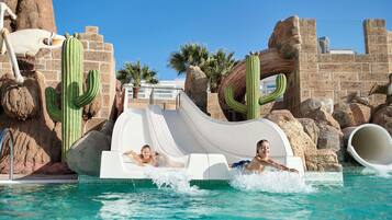 Slide into fun at our resort pool, surrounded by artificial rock formations and cacti.