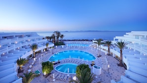 A resort pool area with multiple swimming pools, sun loungers, and palm trees. - Iberostar Selection Lanzarote Park (Yaiza)