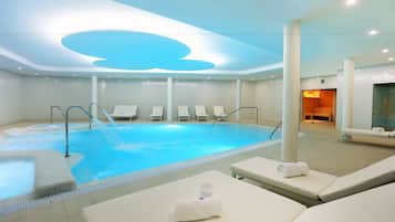 Un área interior de piscina moderna con sillones de descanso y una fuente.