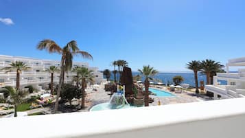 A resort with a pool, palm trees, and a view of the sea.