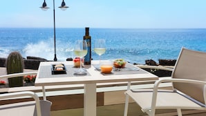 A table with a bottle, two glasses, and a dessert on a deck overlooking the ocean. - Iberostar Selection Lanzarote Park (Yaiza)