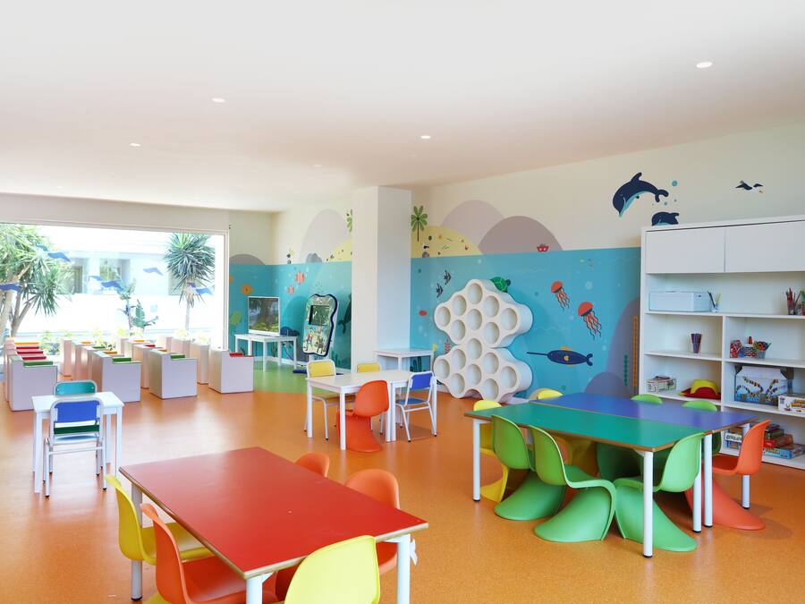 A brightly colored children's playroom with tables, chairs, and educational toys.