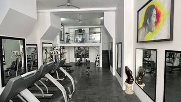 Un gimnasio con cintas de correr, equipamiento de ejercicio y un espejo grande.