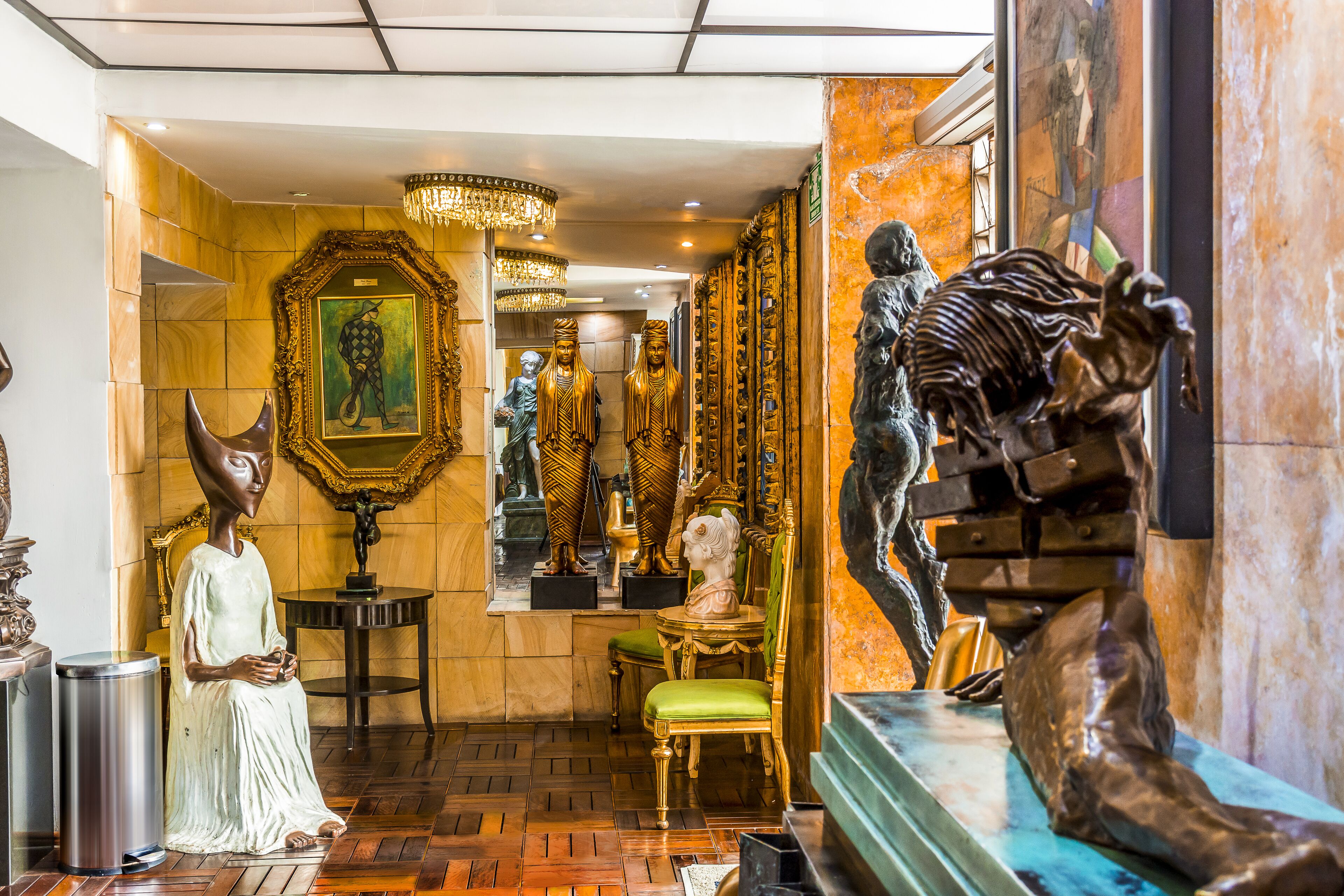 Una lussuosa hall con decorazioni elaborate, tra cui un grande specchio, statue dorate e una poltrona rivestita in verde.