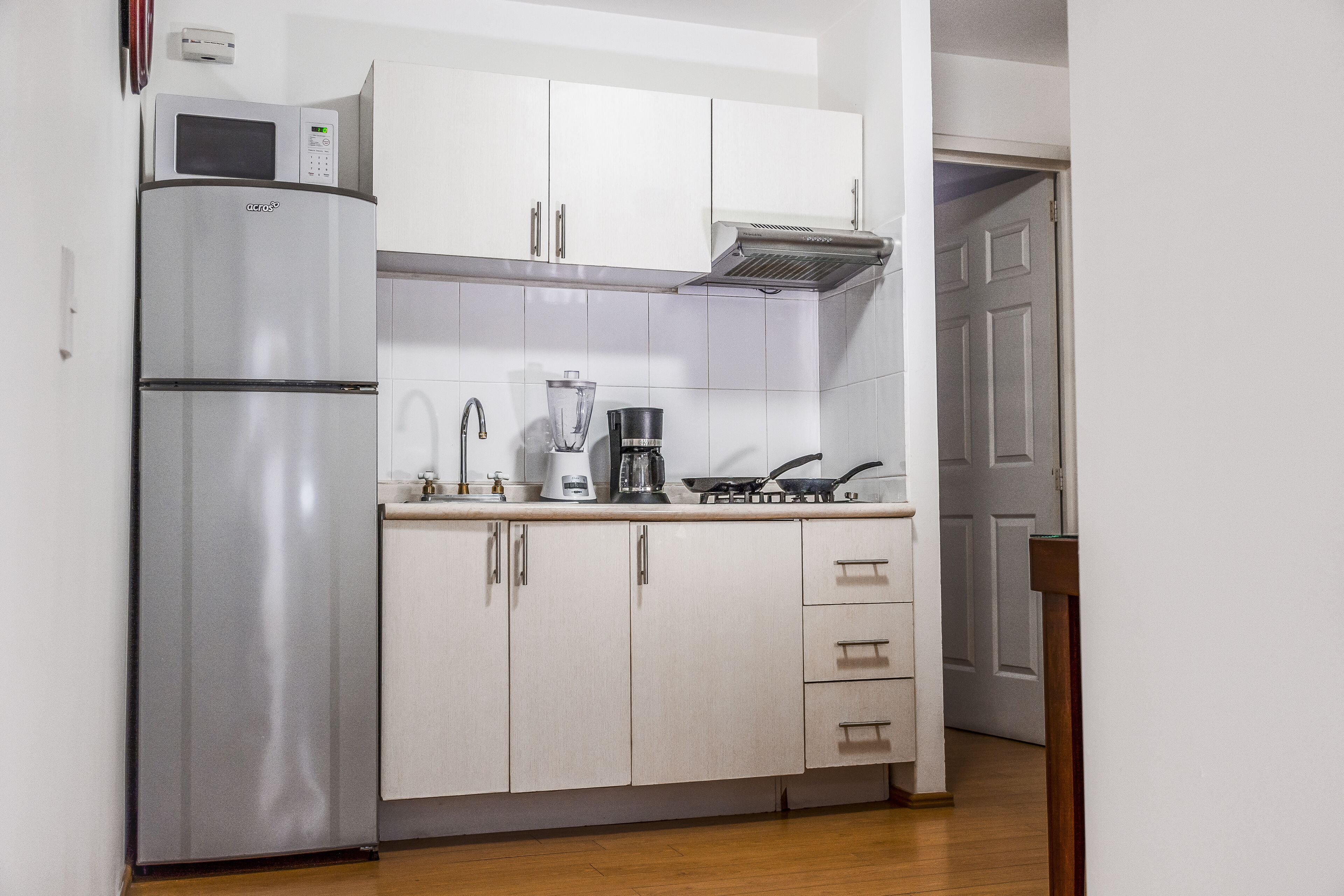 A compact kitchen with a built-in microwave, a coffee maker, and a stove.