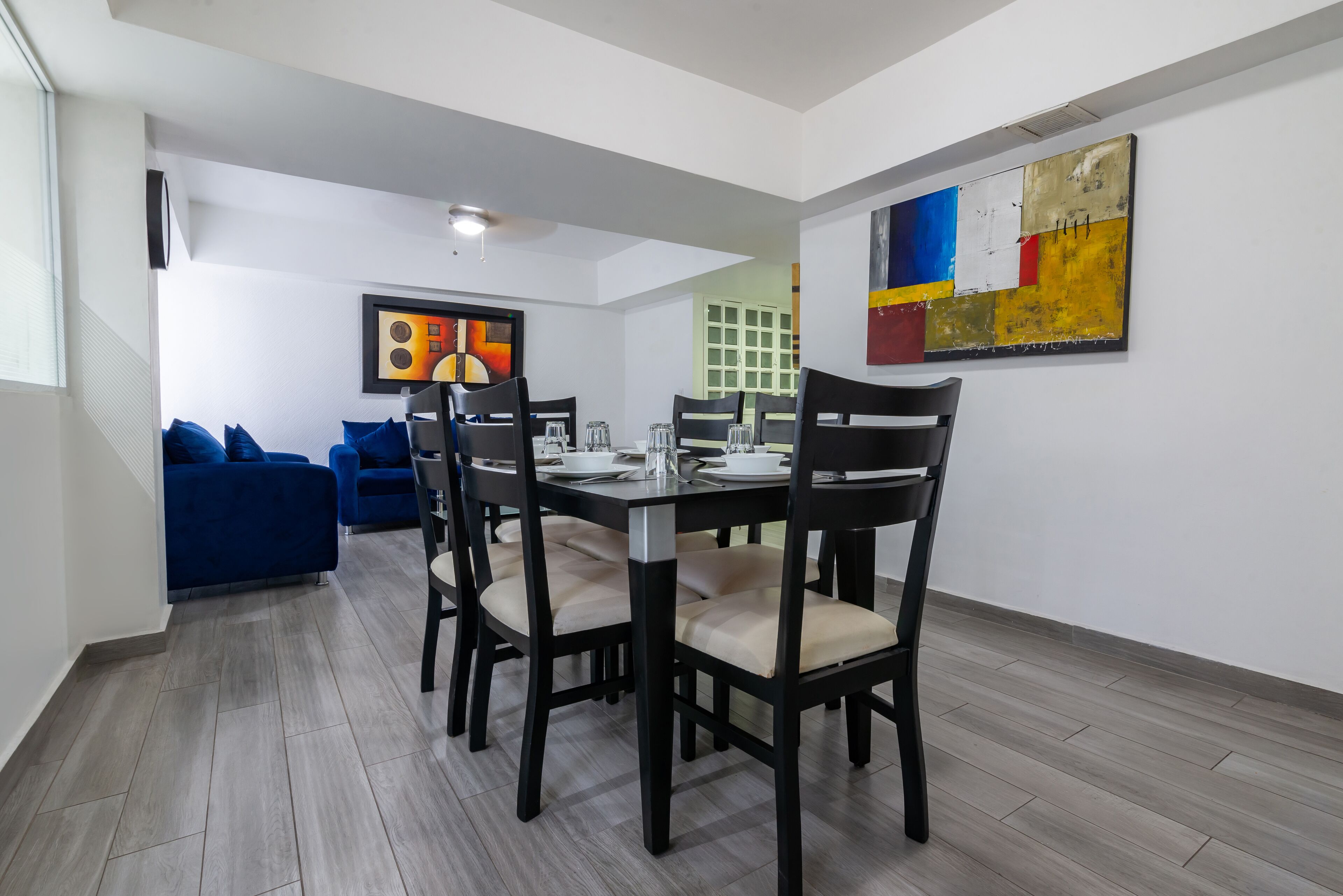 A dining area with a table set for four, surrounded by chairs with cushioned seats.