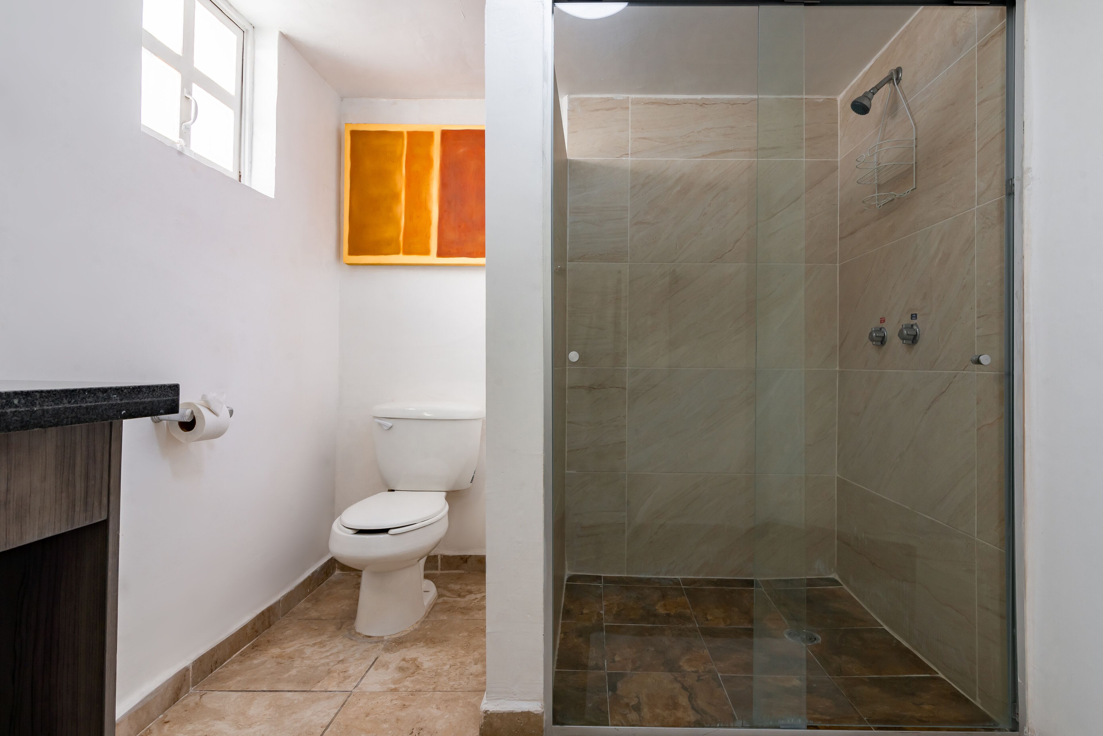 A bathroom with a toilet, a shower with glass doors, and a wall-mounted sink.