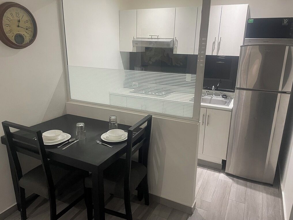 A compact kitchen with a refrigerator, a stove, and a window with blinds.