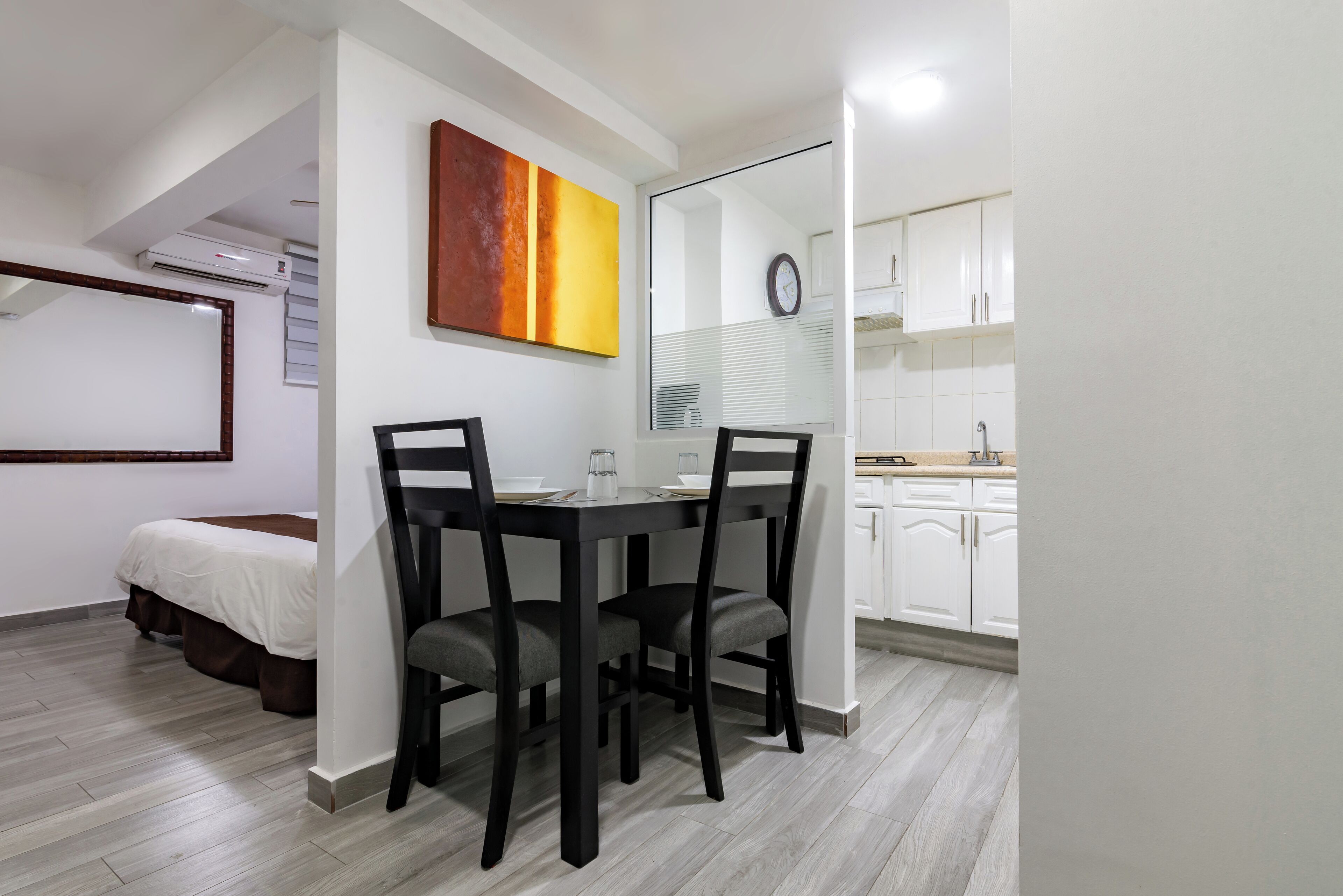 Una habitación compacta con una mesa de comedor y sillas, una cama, una zona de cocina y un ventanal grande.