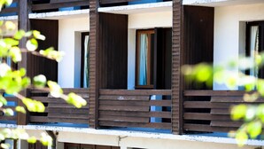 Un edificio de varios pisos con balcones, barandillas de madera y ventanas con cortinas.