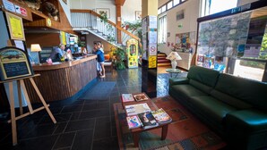 Zona de recepción con mostrador de madera, sofá verde y una mesa baja con revistas.