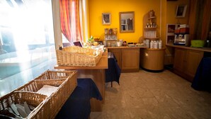 Una cocina con pared amarilla, armarios de madera, una mesa de comedor con mantel azul y cestas de mimbre.