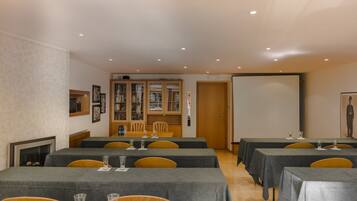 Uma sala de conferências com mesas, cadeiras, lareira e estante.