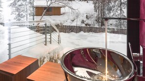 A metal bucket with a red interior, placed on a wooden surface, with a snowy outdoor scene visible through a window. - Hotel Adler (Nova Levante)