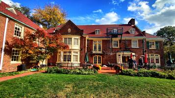 A historic building with a red brick facade, multiple windows, and a central courtyard with outdoor seating.