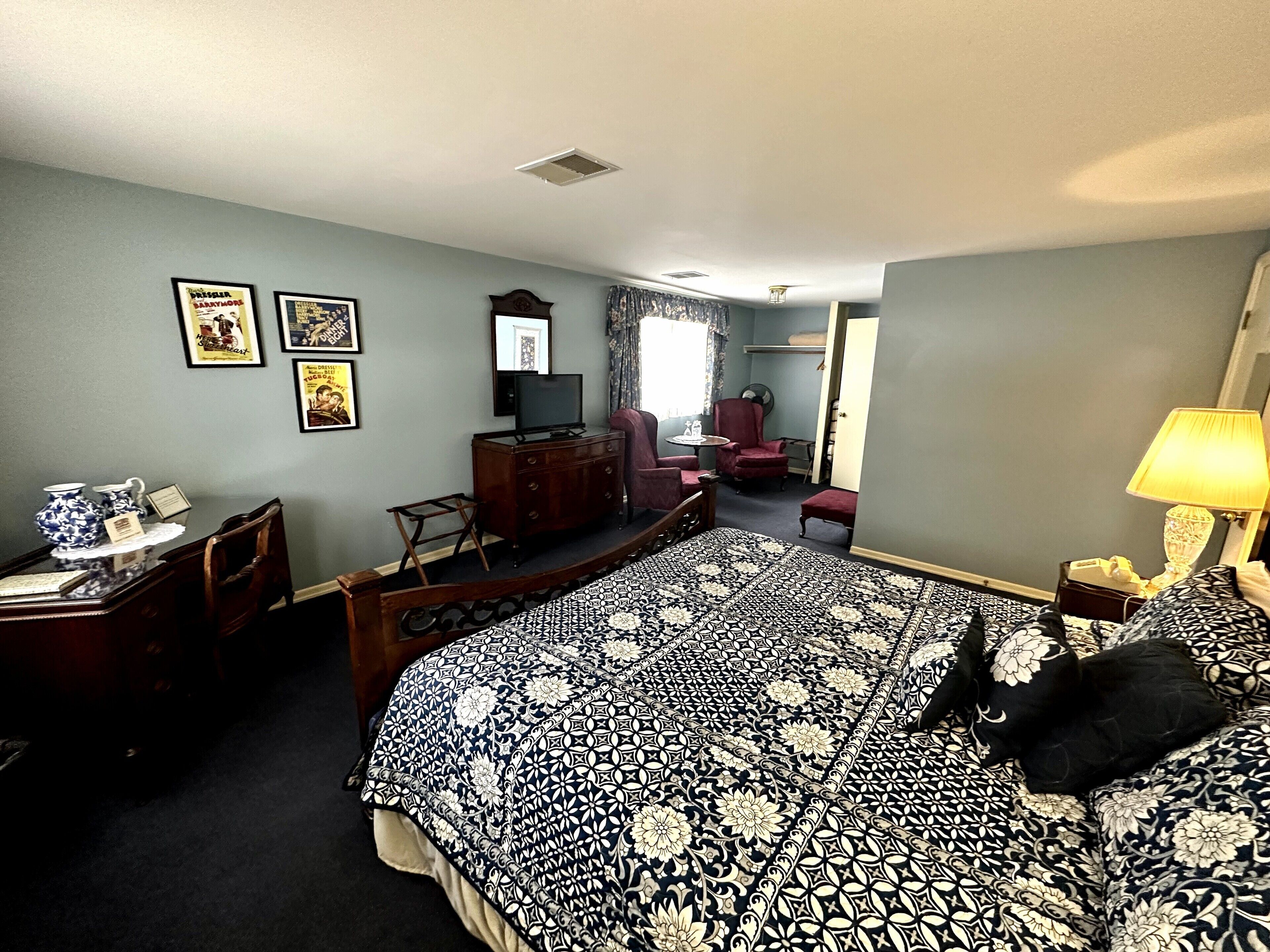 Una habitación de hotel con una cama grande, un escritorio con una silla, un aparador y un televisor.