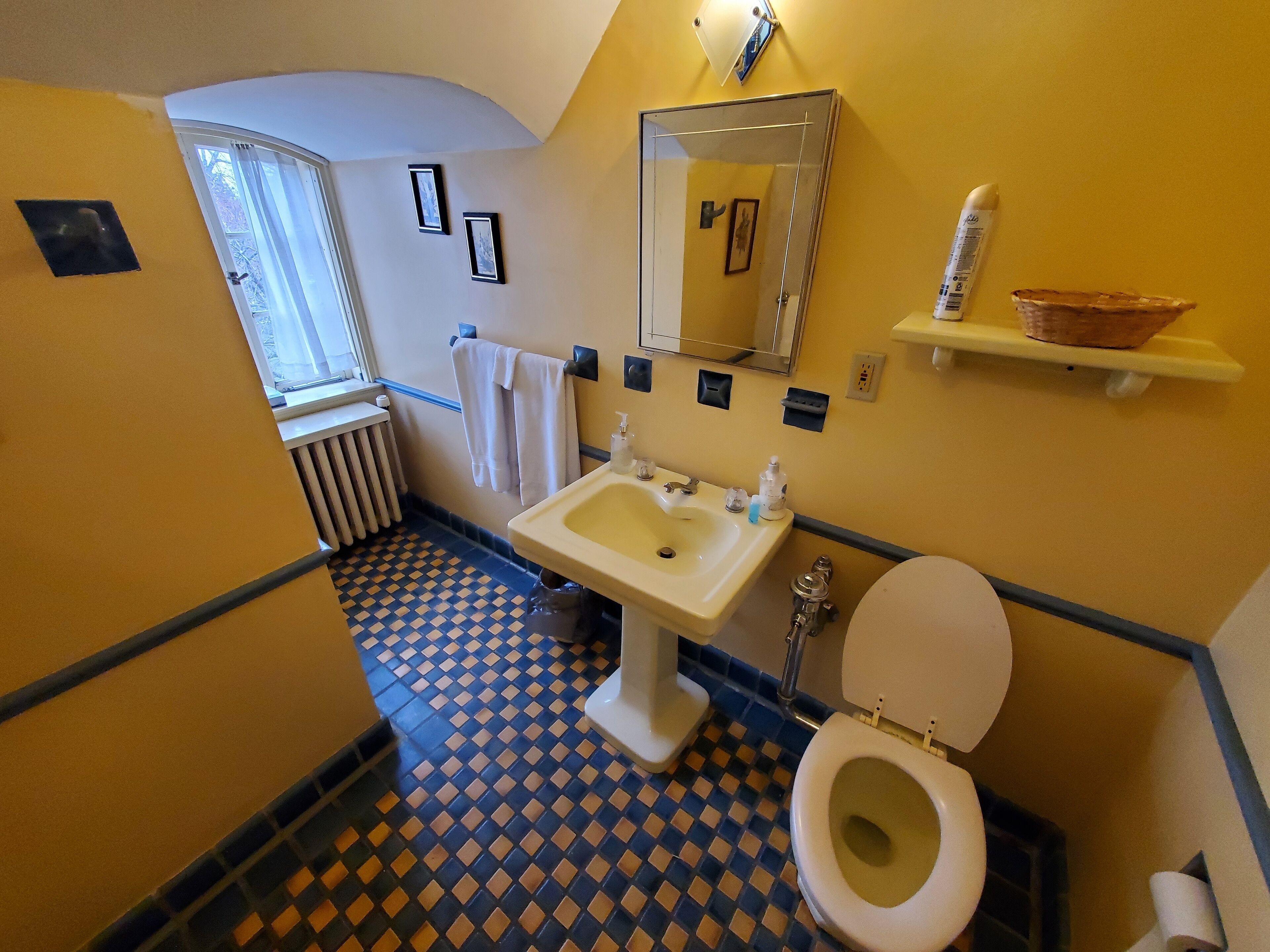 Un baño con piso a cuadros, un lavabo, un inodoro y un espejo.