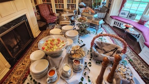 A dining area with a long table set for a meal, surrounded by bookshelves and a fireplace. - Montague Inn (Saginaw)