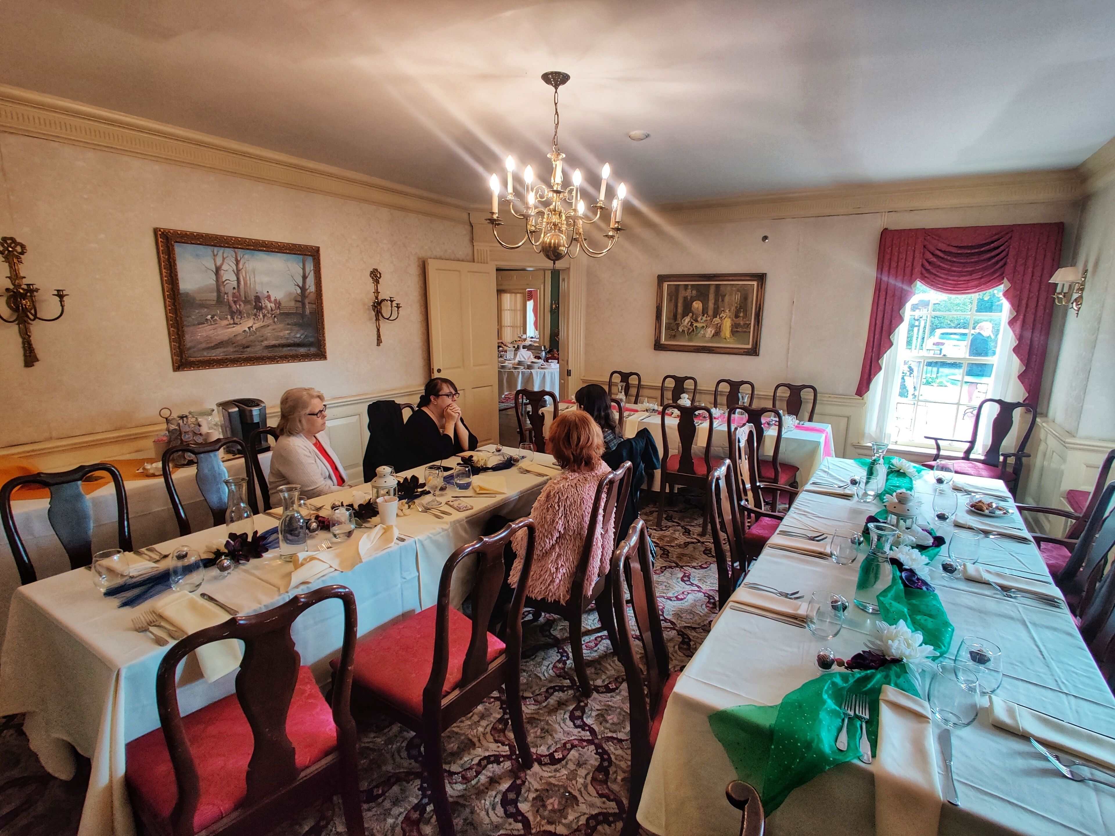 Een formele eetzaal met lange tafels, stoelen en kroonluchters.