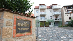 A stone building with a plaque indicating it is a hotel named "Ferienresidenz SCHLOSSLBLICK" located at "Höhe 5a - 06484 Quedlinburg".