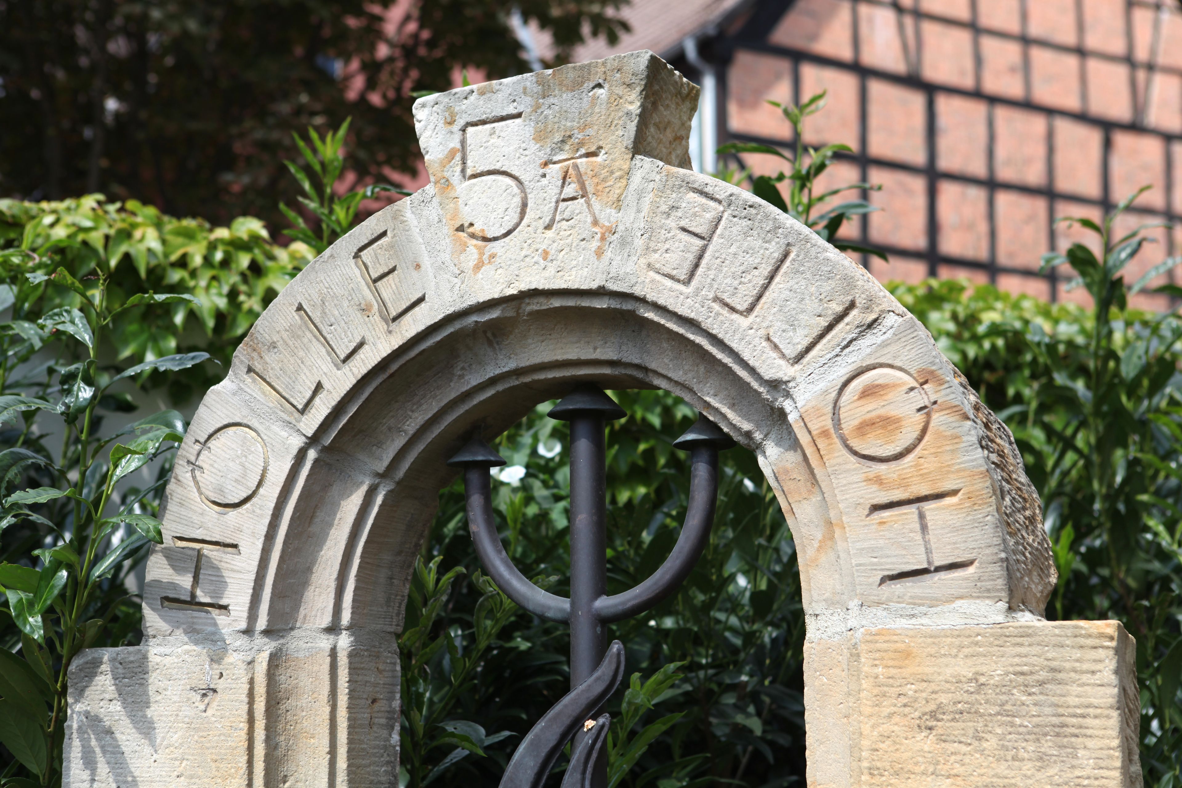 A stone archway with the inscription "HOLLE 5A EDELT" and a metal gate.
