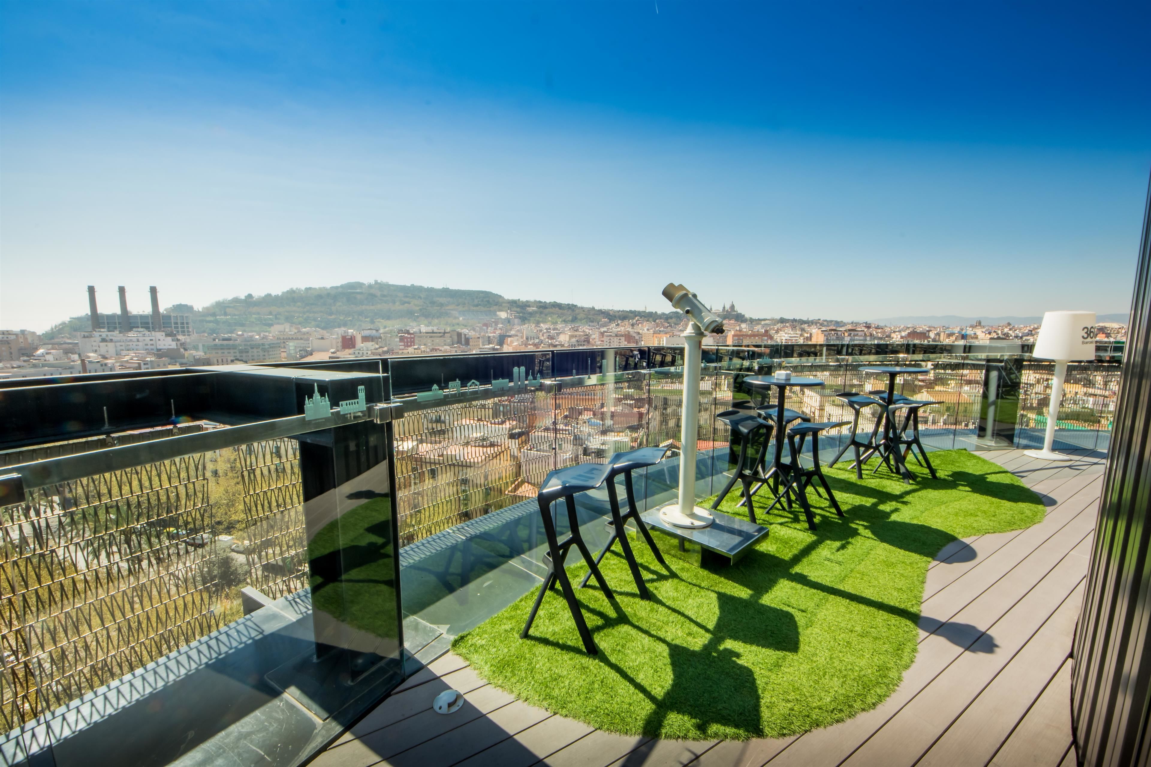 A rooftop terrace with a glass railing, a telescope, and outdoor seating.