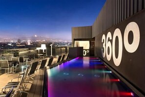 A rooftop pool area with lounge chairs and a large illuminated number '3600'.