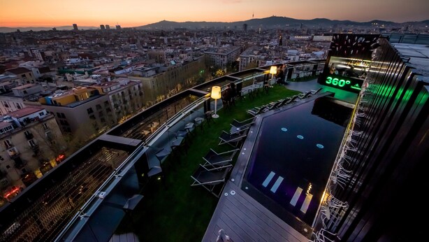 A rooftop terrace with a panoramic city view, a pool, and a temperature display.