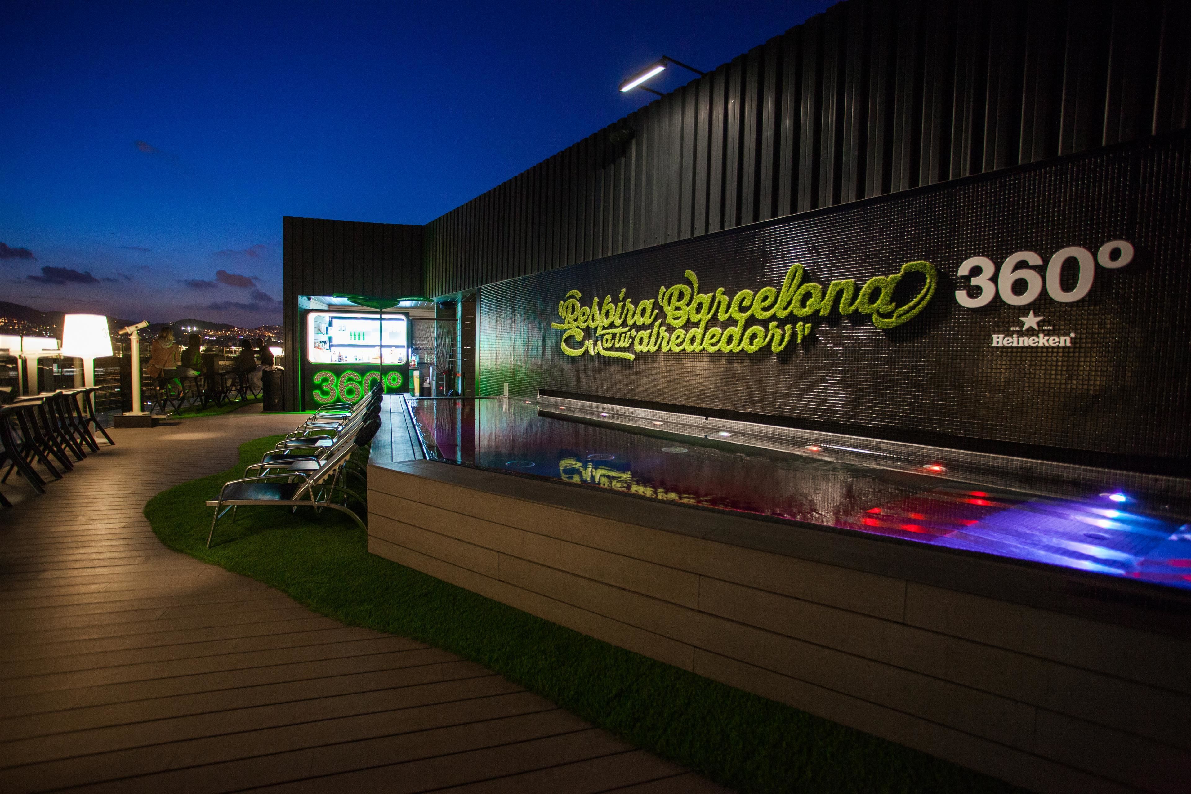 Een modern gebouw met een neonbord waarop 'Despina Barcelona 360º' en 'Heineken' staat.