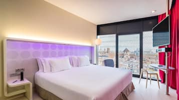 A modern hotel room with a large bed, a small table, and a chair.