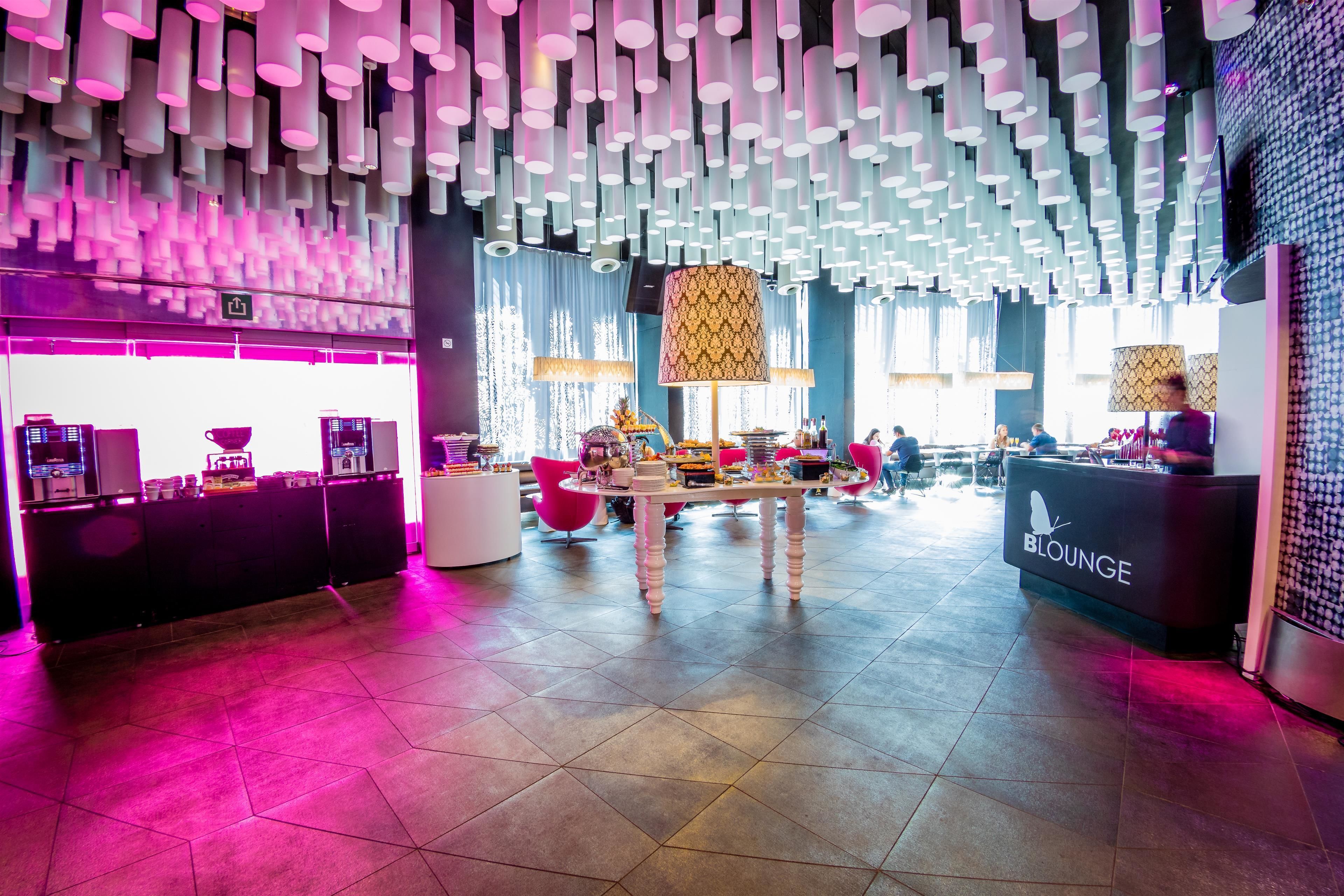 A modern lounge area with a central table, seating, and a 'BLOUNGE' sign.