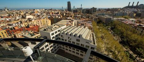 A high vantage point view of a cityscape with modern buildings, a clear sky, and a distant water tower.