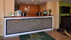 A hotel reception desk with a logo, a monitor, and a plant. - Quality Inn Appleton West (Appleton)