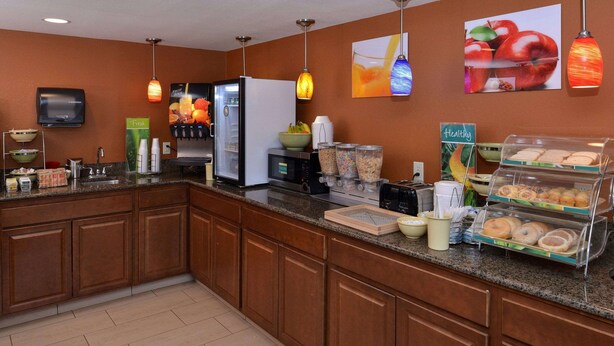 A hotel kitchen with a granite countertop, a refrigerator, a microwave, a coffee machine, and a breakfast display with pastries. - Quality Inn Appleton West (Appleton)