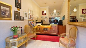 A hotel lobby with a reception desk, framed pictures on the walls, a red carpet, and a large mirror. - Hotel & Apartments Zarenhof Berlin Prenzlauer Berg (Berlin)