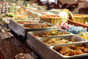 Ein reichhaltiges Buffet mit verschiedenen Speisen, darunter Fleisch, Gemüse und Gebäck.