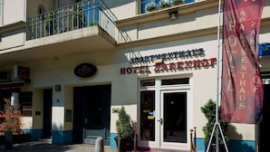 A hotel entrance with a red carpet, a balcony, and a flag. - Hotel & Apartments Zarenhof Berlin Prenzlauer Berg (Berlin)