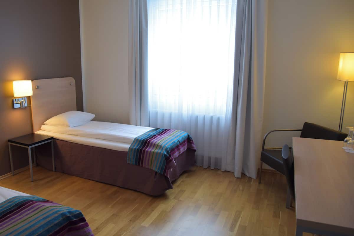 Ein Hotelzimmer mit Bett, Nachttischen, Schreibtisch und Stuhl.