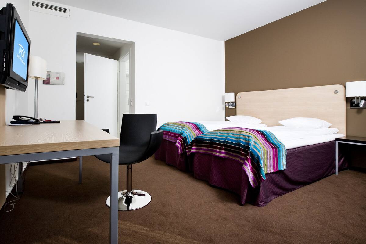 Una habitación de hotel con escritorio, silla, cama y mesitas de noche.