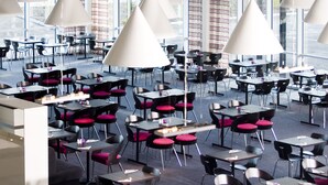 A spacious indoor dining area with multiple tables and chairs, large windows, and hanging pendant lights. - Hotell Charlottenberg (Charlottenberg)