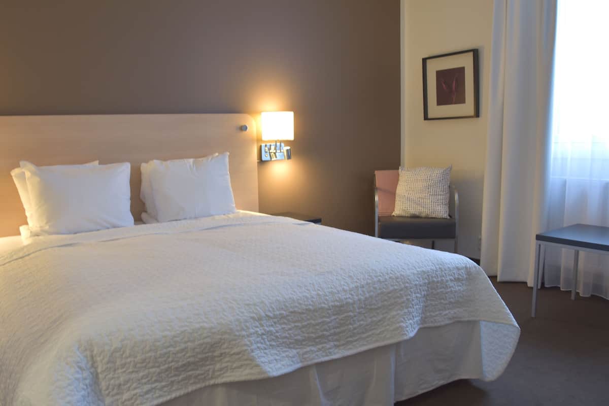 Ein ordentlich bezogenes Bett mit weißen Laken in einem Hotelzimmer.