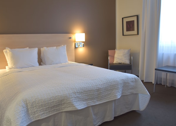 Una cama bien hecha con ropa blanca en una habitación de hotel.