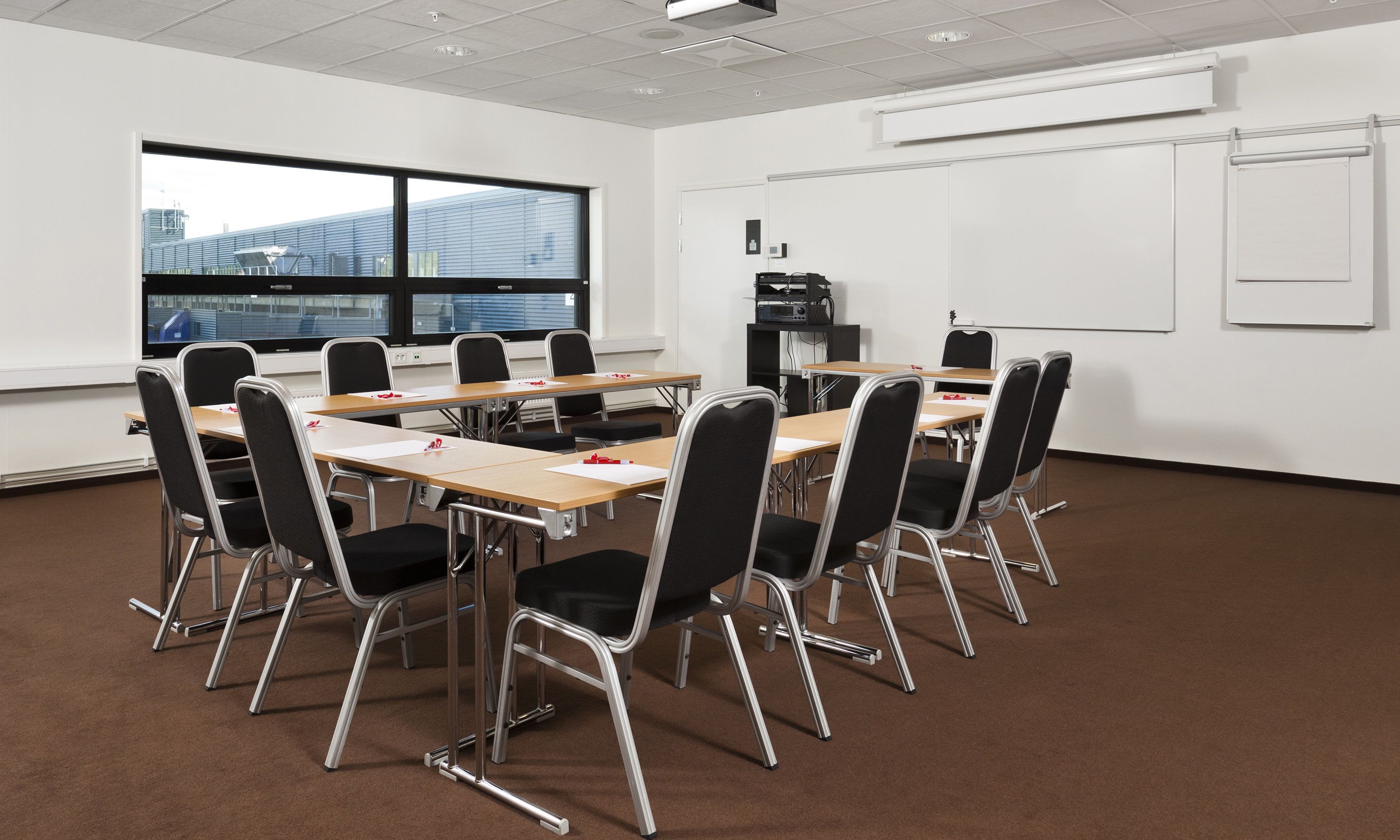 A conference room with a large window, whiteboard, and projector.