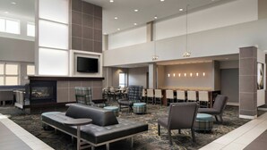 A spacious lobby with a fireplace, comfortable seating, a TV, and a bar area. - Residence Inn Newport News Airport (Newport News)