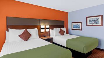 A hotel room with two beds, a wooden headboard, bedside lamps, and a U.S. Army framed picture on the wall.