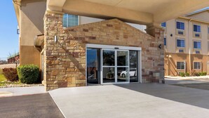 A hotel entrance with a stone facade, glass doors, and a covered walkway.