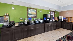 A breakfast bar with various food and drink dispensers, a coffee machine, and a refrigerator.