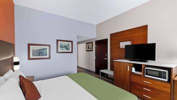 Ein Hotelzimmer mit Bett, Fernseher, Mikrowelle und einem Holzschrank.