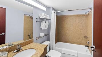 A bathroom with a granite sink, a toilet, a bathtub, and a shower curtain.